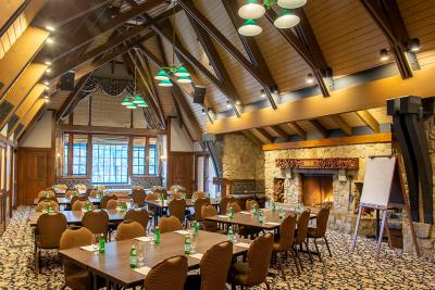 Image of conference room at UCLA Lake Arrowhead Lodge including six tables an easel and many chairs positioned around a fireplace.