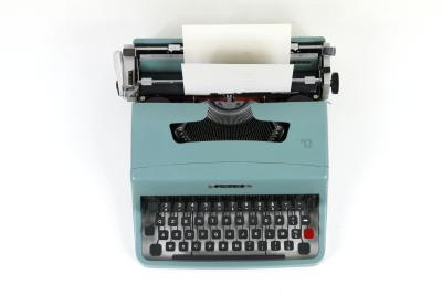 Top down view of a teal and black typewriter with a piece of paper partially spooled through.