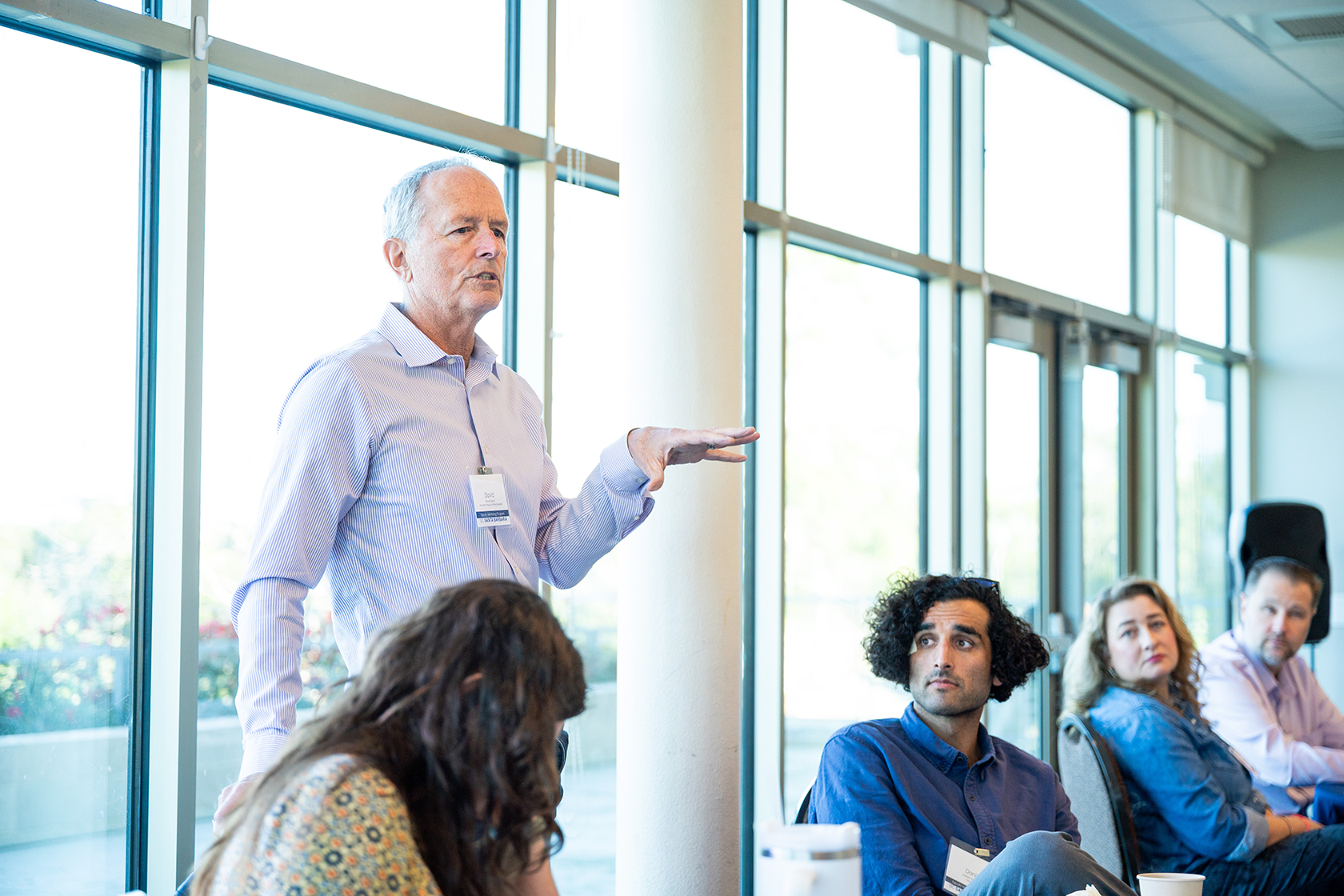 four seated people listening to one person standing