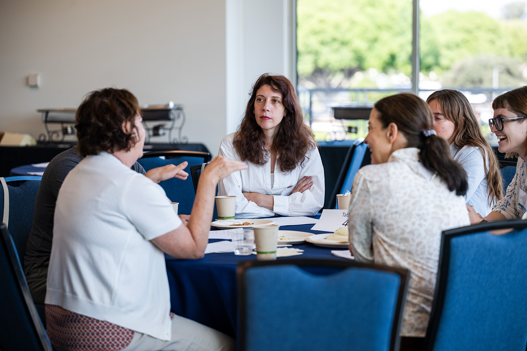 five women gather around a table while discussing
