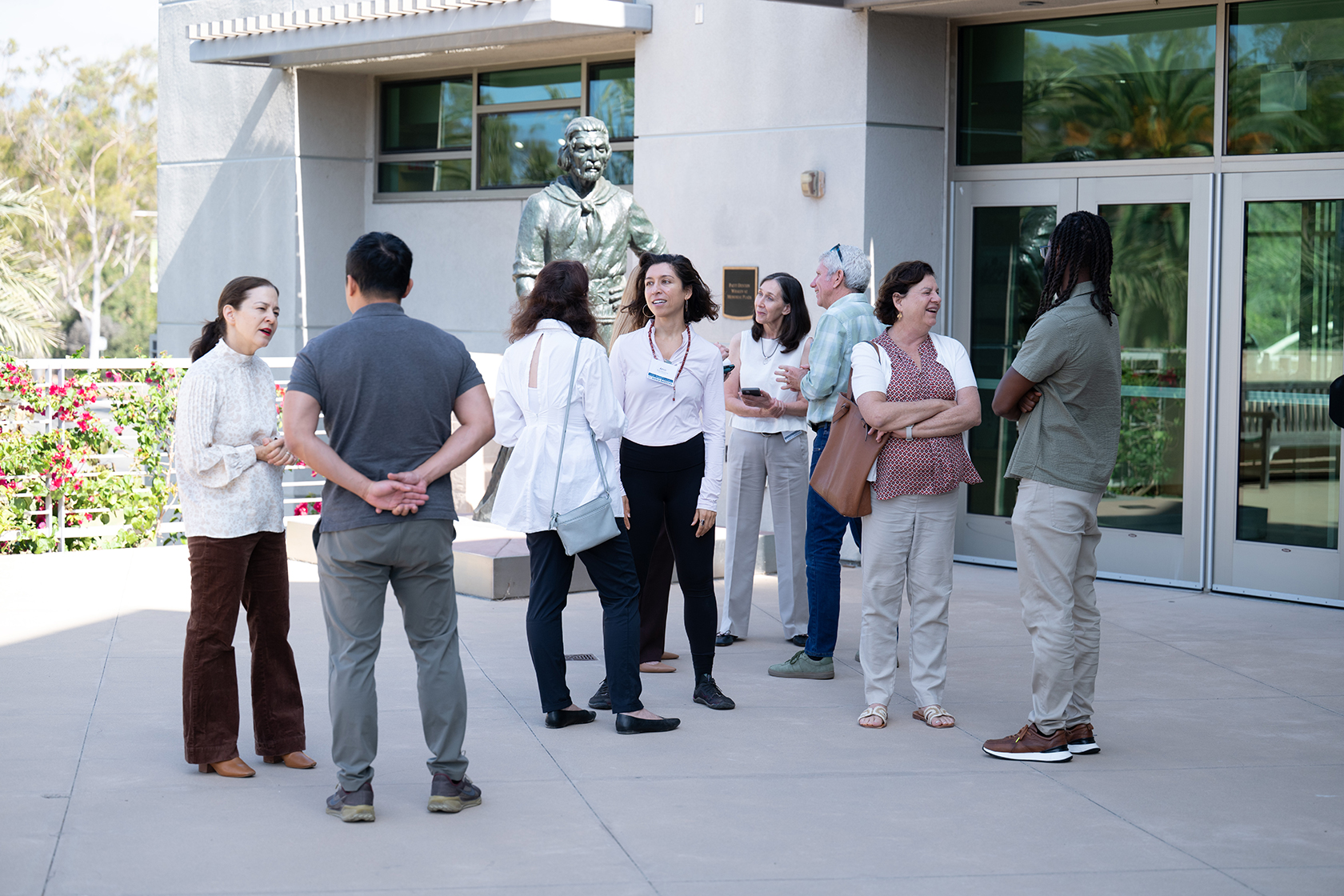 Mentoring program attendees stand outside a building and gather in small groups to talk