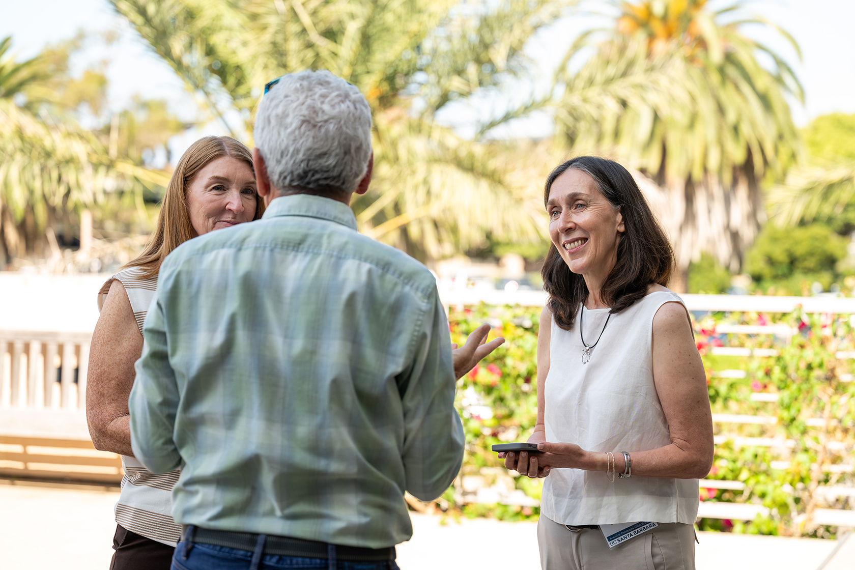 Attendees pose outside for a group photo with palm trees in the background