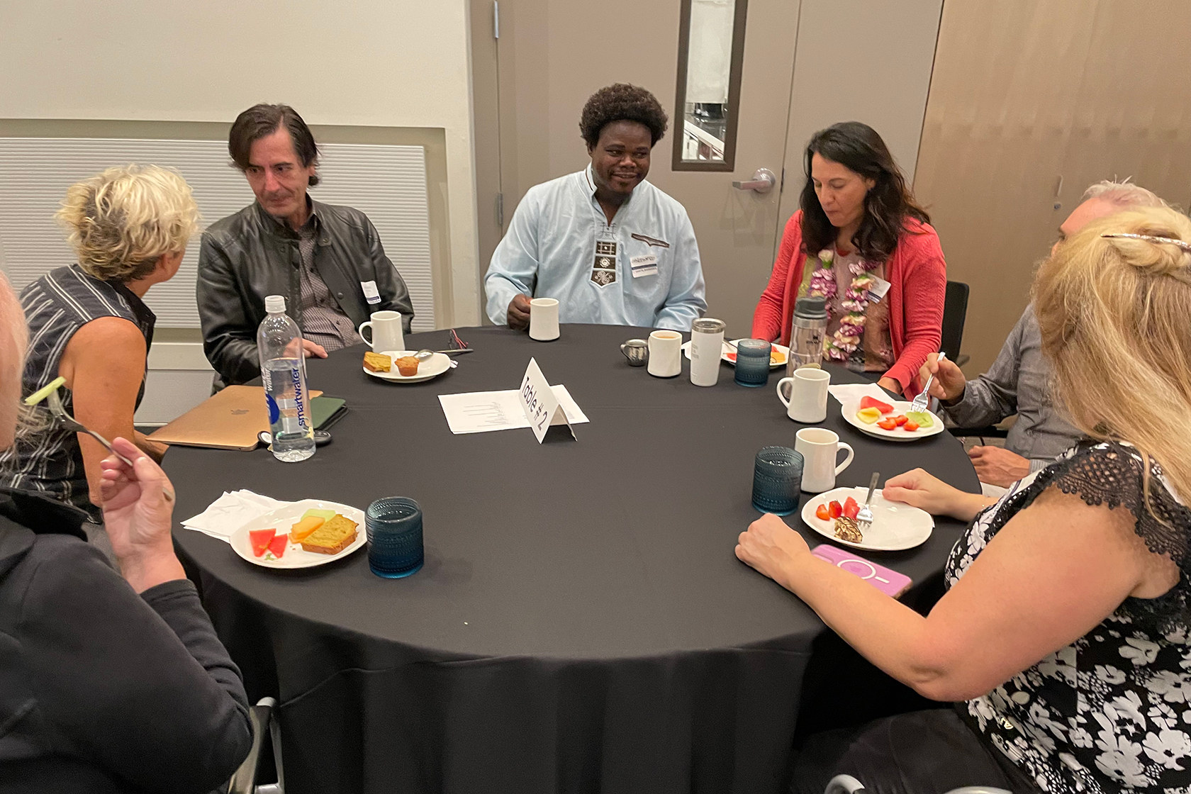 seven people seated at a round table eating