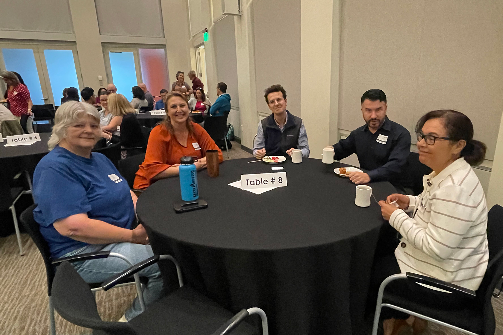 five people posing for a photo around a circular table