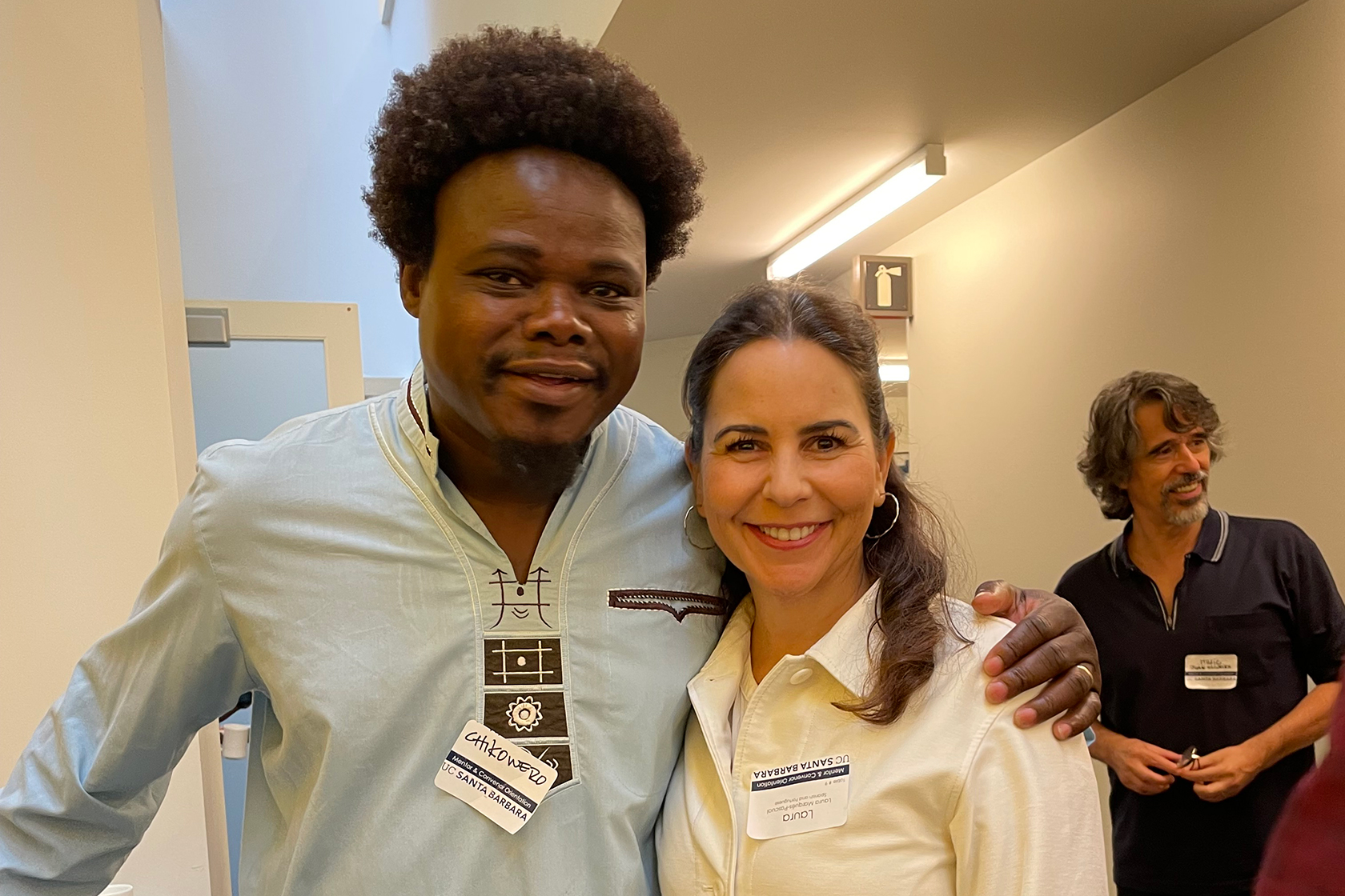 two people facing forward each with an arm around the other