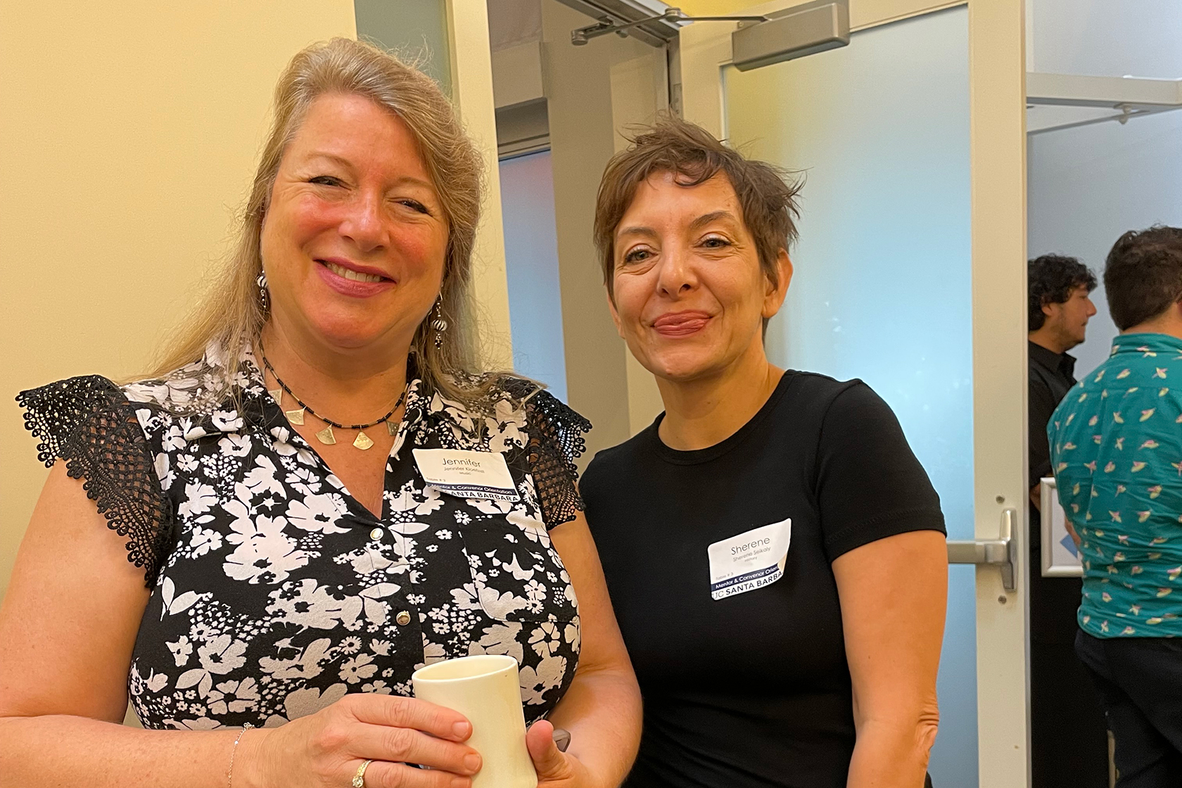 two people wearing black shirts facing forward and smiling