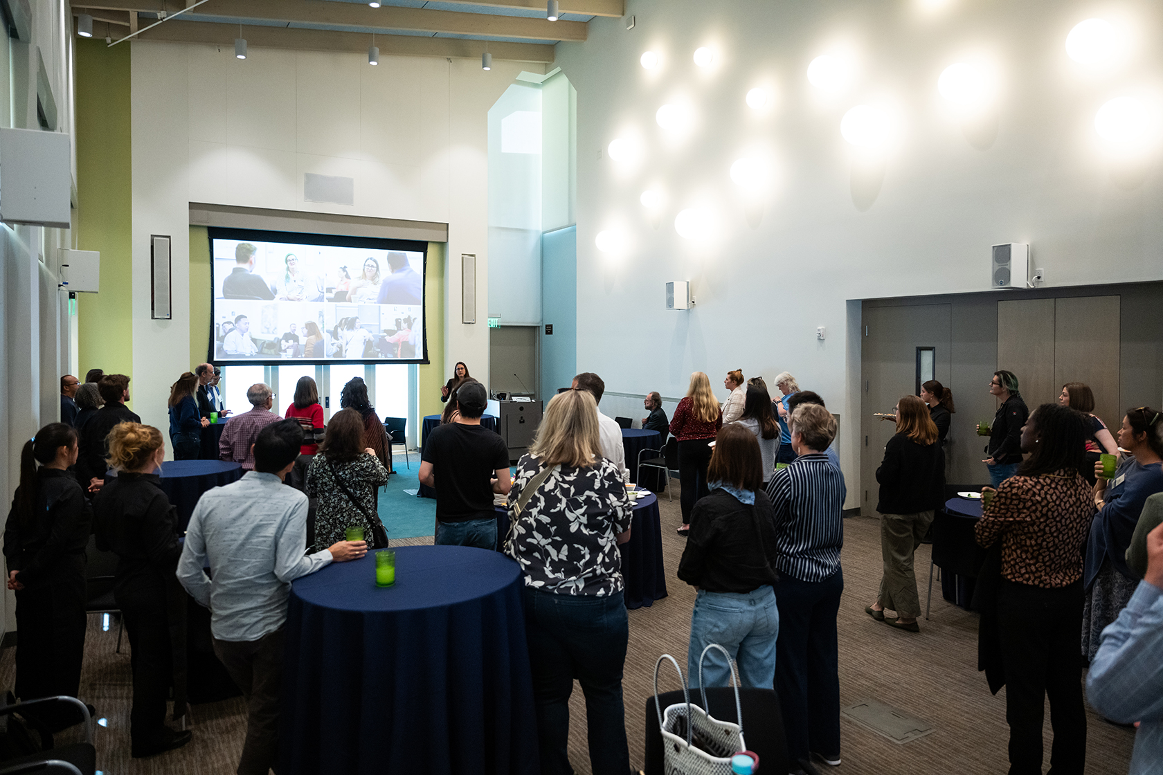 large group of people standing in a conference room with some photos projected onto a screen