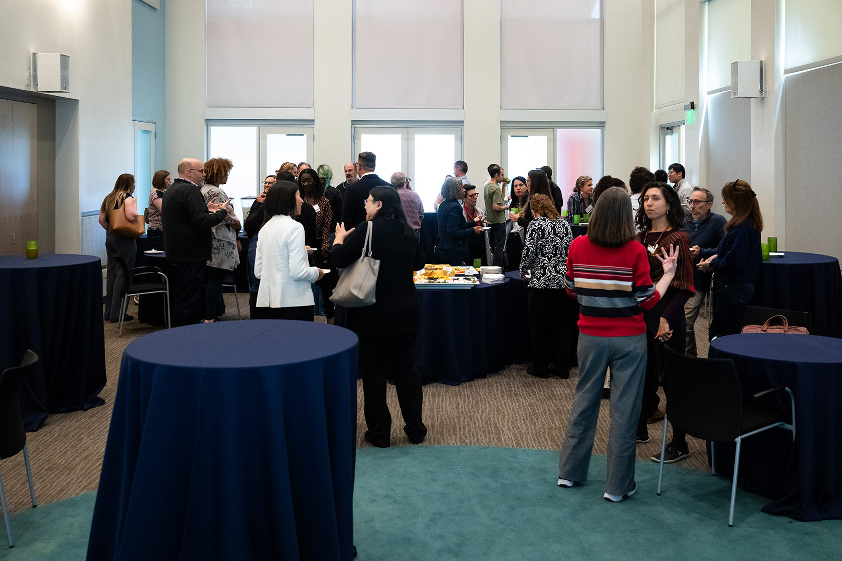 conference room with several blue circular tables and groups of people gathering