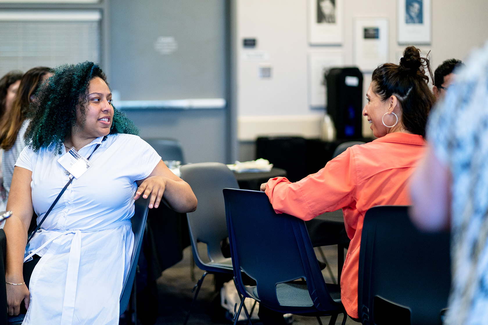 two people seated at different tables one turned around talking with a person behind
