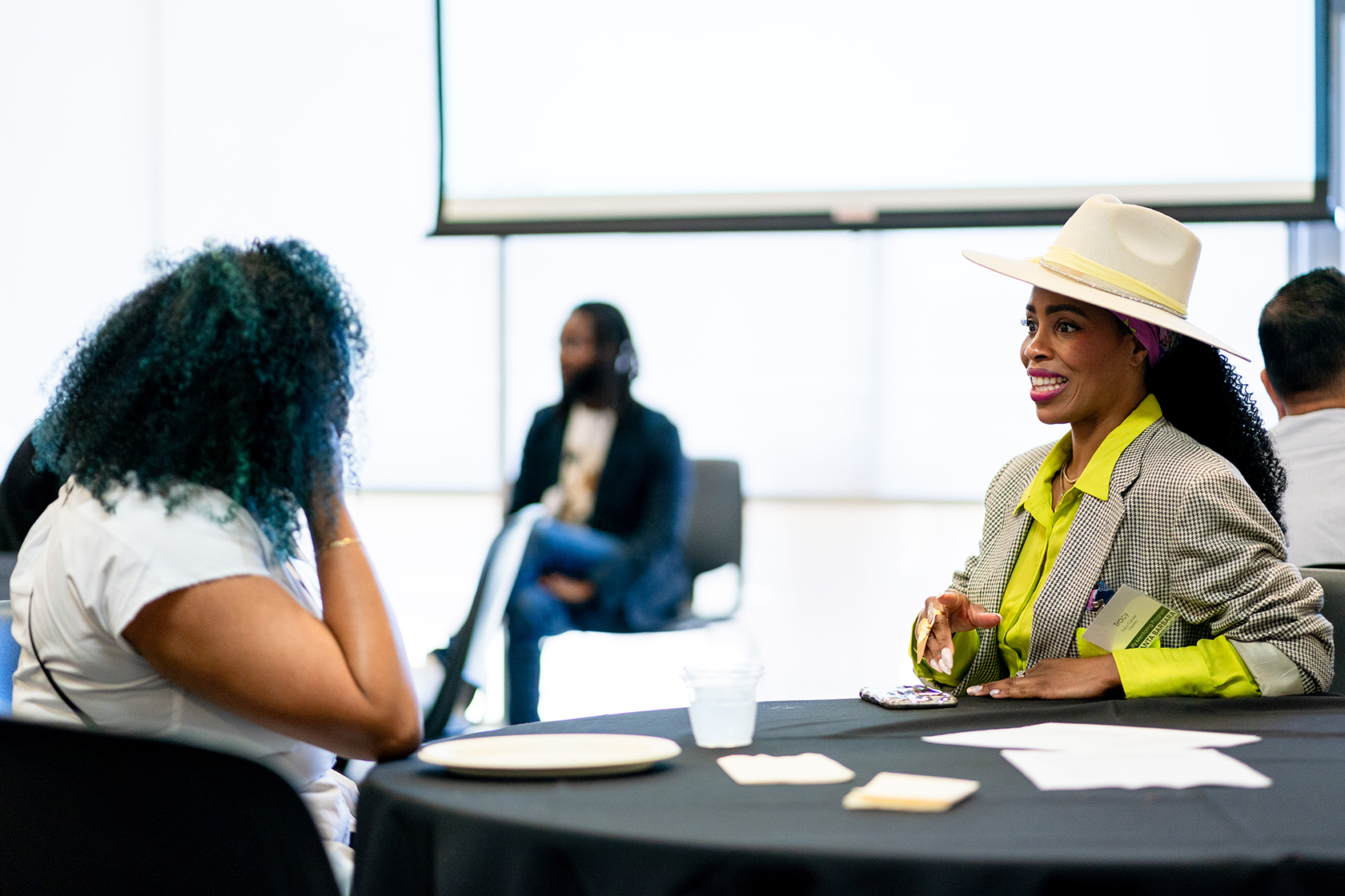 four people seated two conversing in the forefront of the image