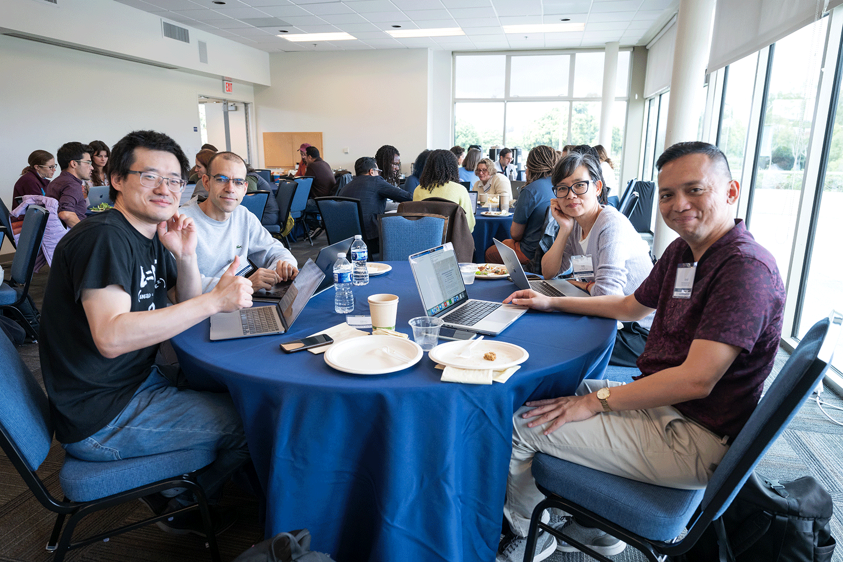 four people seated around a blue circular table smiling for the photo
