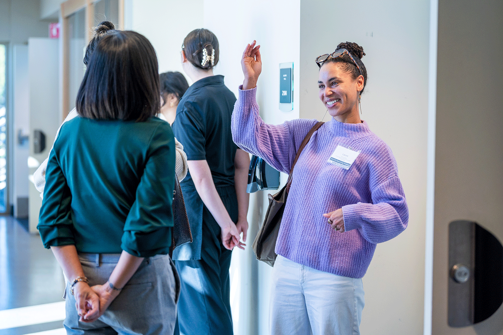 several people standing with one in a lavender sweater smiling with arms raised