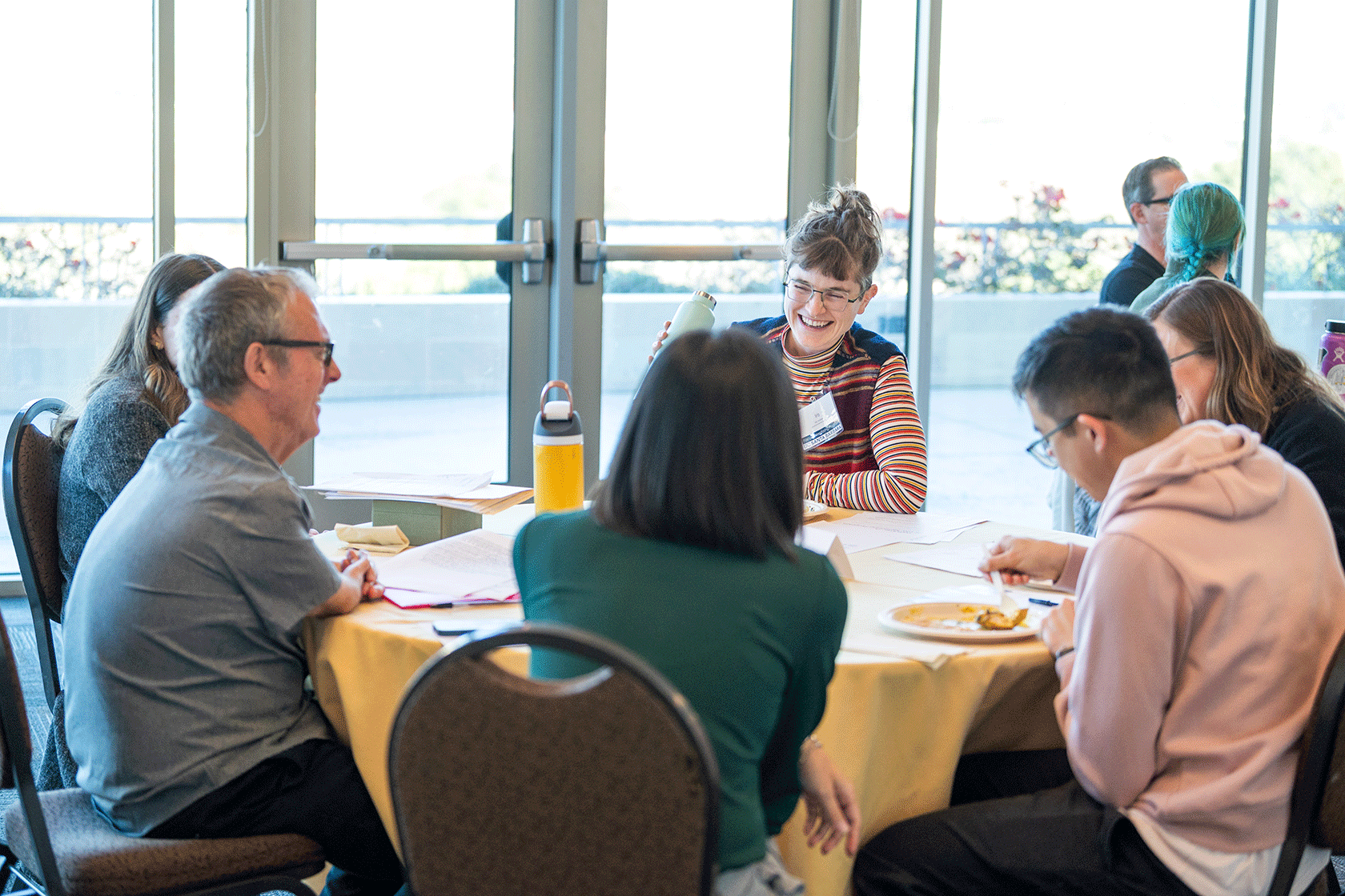 six smiling people seated around a circular table