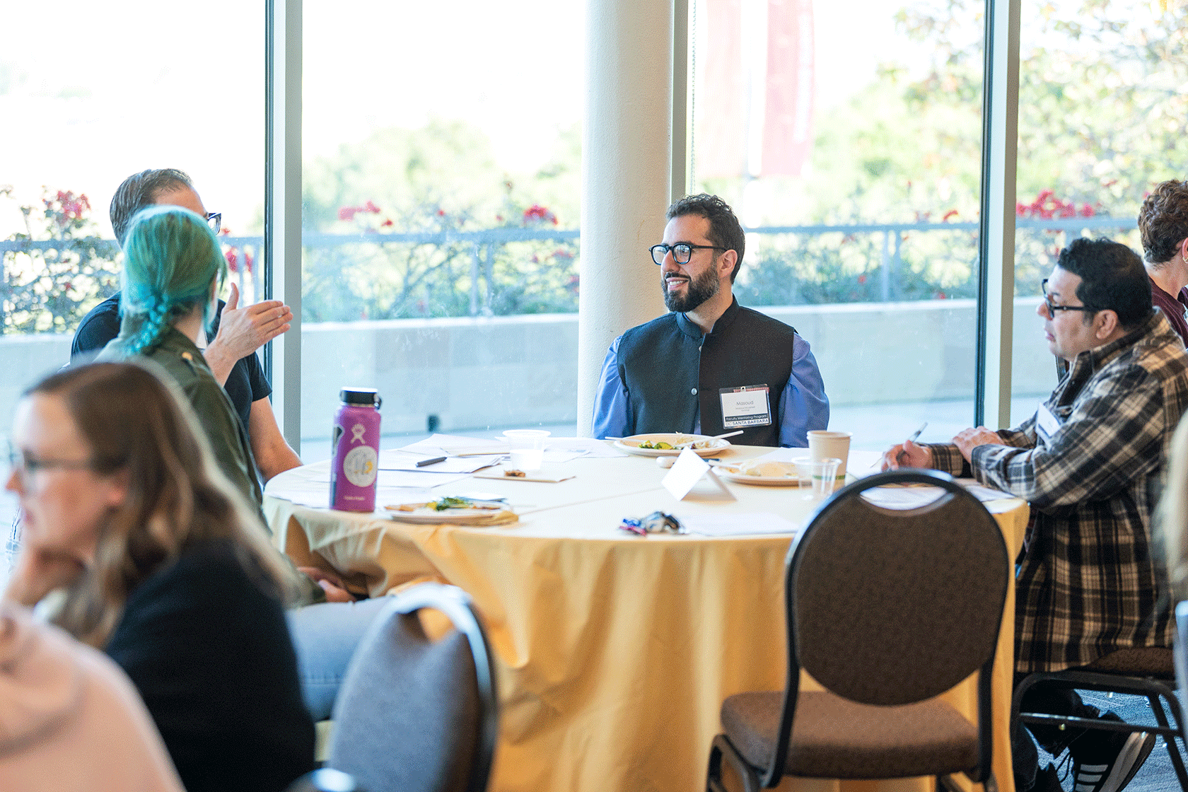 several people seated at a round table talking